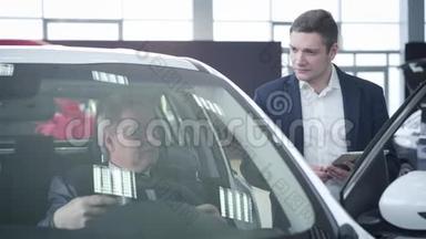 自信的年轻白种人汽车经销商咨询<strong>老客户</strong>坐在车里。 成功成熟